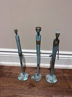Three blue patina metal statues standing on bases