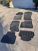 Eight Audi rubber winter mats laid out on driveway showing sizes and tread patterns