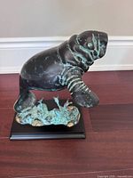 Full view of bronze manatee sculpture on base