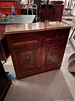 Front view of wooden cabinet showing drawers, paneled doors and veneer detail