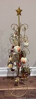 Full view of gold metal ornament display stand with all attached ornaments