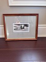 Front view of framed photograph on floor showing frame, mat, and image
