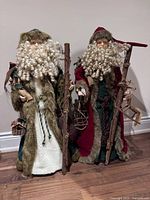Front view of both Santa figures showing robes, beards, staffs, accessories