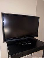 Front view of Sharp AQUOS 50" TV on stand with remote
