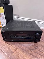 Front view of Sony AV receiver on floor showing display, controls, headphone jack, volume knob