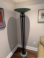 Full view of tall torchiere floor lamp in corner showing base, rods, and shade