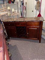 Front view of wooden sideboard showing stone top, drawers, wine rack, cupboards