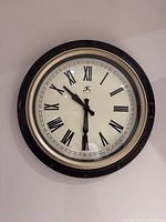 Front view of round wall clock showing face, numerals, hands, and bezel