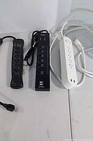 Three devices laid out: APC power bar, black USB charger, white power bar