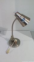 Full view of brushed chrome desk lamp with cord wrapped around base