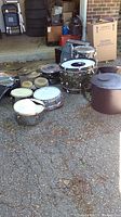 Various drum shells, hard case, cymbal bag on driveway