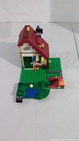 Front view of Lego house on green base with door, pond and garden