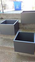 Three gray Ikea Eket storage cubes displayed on steps