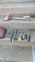 Overall view of hammer, hacksaw, screwdrivers, sandpaper on steps