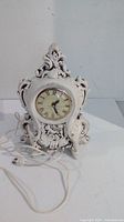Full view of ornate ceramic mantle clock with cord