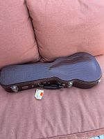 Full view of brown crocodile-pattern Kala ukulele hard case on cushion