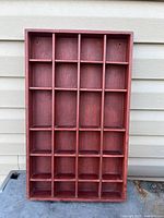 Front view of red-stained wooden display tray showing all compartments