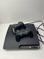 PS3 Slim console top view with two controllers atop