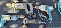 Overview of four corded tools laid out: two drills, one hammer drill, one grinder