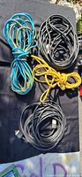Four coiled extension cords on black cloth: blue, black, yellow, grey