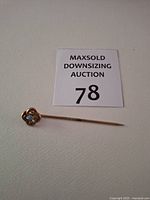 Full view of gold stick pin beside lot number card