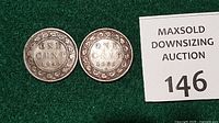 Reverse sides of both coins with auction tag