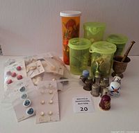 Group view of buttons in containers and bags, thimbles and brass mortar with pestle