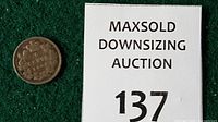 Reverse crowned wreath with denomination "5 CENTS 1900" on Canadian coin beside lot marker