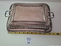 top view of rectangular silver-plated covered dish with tape measure for scale
