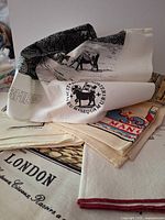 Stack of printed souvenir linen tea towels showing London, Manchester and pastoral designs