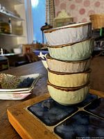 Stack of six pastel textured bowls with tile coasters visible
