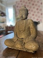 Front angled view of seated Buddha statue showing robe and pose