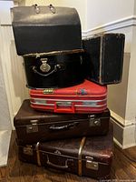 Stack of six vintage suitcases showing variety of shapes and colours
