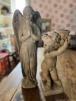 Angel and cherub statues side by side on table