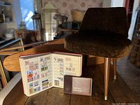 Stool, ironing board, open stamp album, Olympic booklet
