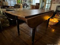 Table angled view showing drop leaves raised, turned legs visible