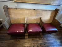 Front view of pew showing three burgundy seats and wood back