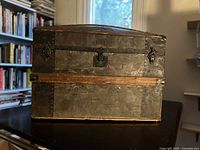 Front view of metal-clad wood steamer trunk with lock and wood slat