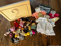Wooden box front showing number 2, finger puppets spread, and two doll outfits