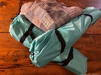 Two turquoise chair carry bags and folded wool quilt