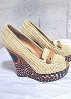 Side view of both raffia wedge shoes showing woven uppers and patterned wedge