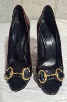 Front view of both pumps displaying horsebit hardware and open toe design