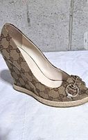 Side view of right shoe showing GG canvas pattern, jute wedge heel, horsebit hardware