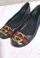 Oblique view of both flats showing black leather, green-red web, gold GG hardware