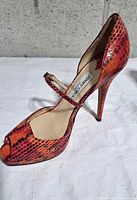 Left side view of right pump showing snake print, peep toe, strap, heel