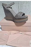 Side profile of wedge sandal on box with dust bags visible