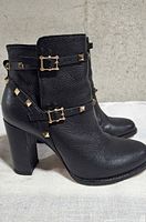 Side profile showing black leather, block heel, studded straps