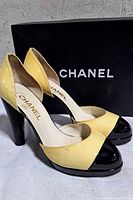 Side view of both pumps in front of Chanel box