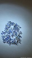 Cluster of small round faceted light blue-purple stones on white background
