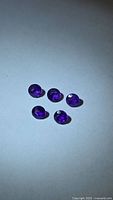 Five round deep-purple amethysts on light background